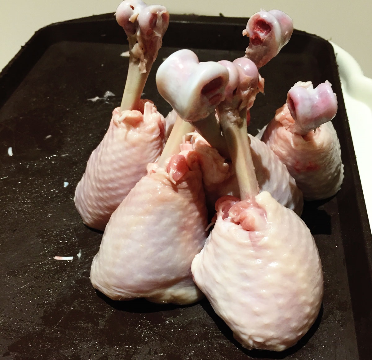 Prepare your chicken legs by pulling back the meat from the bone.
