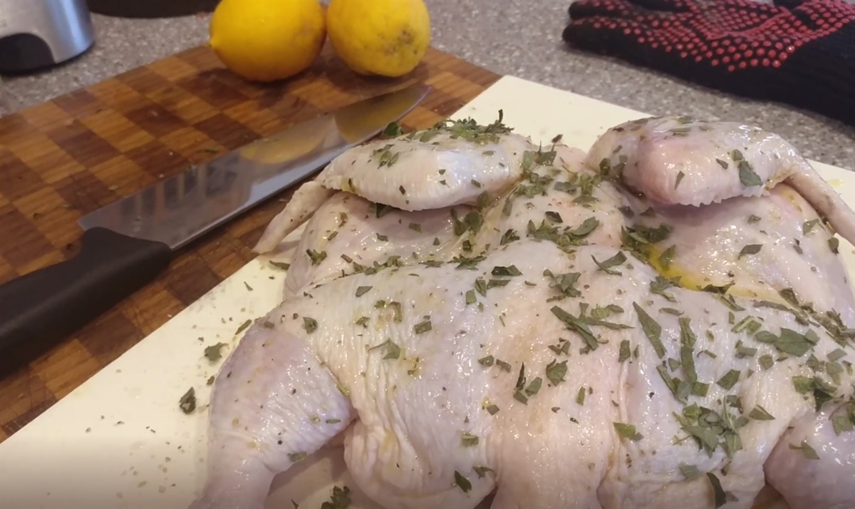preparing lemon herb chicken charcoal bbq recipe - drizzle with olive oil, add seasoning and herbs.